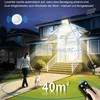 A woman walking a dog at night in front of a house, illuminated by a solar-powered light. Produktbild-Vorschau