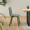 A gray dining chair is shown in a room with a wooden floor and a table in the background. Produktbild-Vorschau