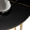 A close-up view of a black marble-effect tabletop with gold veining, and a white bowl. Voir les images du produit