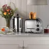 A kitchen counter scene with a toaster, kettle, and flowers. Anteprima dell’immagine prodotto