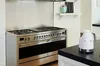 A modern kitchen with a stainless steel range and a white SMEG kettle on a black countertop. Náhled obrázku produktu