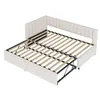 A beige upholstered bed frame with the mattress support extended, showing its pull-out bed mechanism. Voir les images du produit