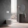 A modern bathroom with a toilet, sink, and mirror, overlooking a city skyline. Produktbild-Vorschau