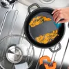 A hand is cleaning a dirty frying pan in a sink. Voir les images du produit
