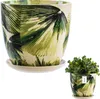A ceramic pot with a green leaf pattern and a matching saucer, shown with a small plant in a separate, smaller pot. Voir les images du produit
