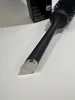 A black GHD hair brush is placed on a white surface, with its packaging visible in the background. Podgląd zdjęcia produktu