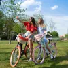 Two young women are taking a selfie with their bicycles in a park on a sunny day. Produktbild-Vorschau