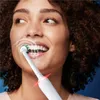 A woman is brushing her teeth with an electric toothbrush. White lines indicate the cleaning action. Produktbild-Vorschau