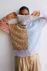 A person wearing a colorful, patchwork turtleneck sweater. Produktbild-Vorschau
