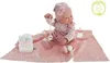 A baby doll is sitting on a pink blanket with a diaper and a baby bottle. Anteprima dell’immagine prodotto