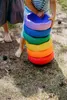 Children playing with rainbow stacking stones outdoors. Voir les images du produit