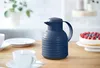 A navy blue insulated carafe sits on a wooden table next to a cheesecake and a cup of coffee. Voir les images du produit
