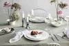 A beautifully set dining table with plates, wine glasses, candles, and floral arrangements. Podgląd zdjęcia produktu