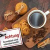A flat lay image featuring coffee, cookies, and cinnamon sticks, with a security sign in the foreground. Produktbild-Vorschau