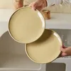 Two plates are being held by hands over a sink area. Produktbild-Vorschau