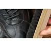 A close-up of a black leather shoe being brushed with a shoe brush. Produktbild-Vorschau