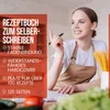 A woman is shown in a kitchen setting, with a recipe book and ingredients. Produktbild-Vorschau
