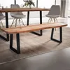 A wooden bench with black metal legs is placed on a rug in front of a dining table with chairs. Náhled obrázku produktu