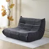A dark gray sofa is placed on a light gray rug in a room with white walls and decorative molding. Produktbild-Vorschau