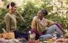Two young women are having a picnic outdoors, with food and drinks spread out on a blanket. Voir les images du produit