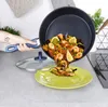 A hand is pouring paella from a frying pan onto a plate. Produktbild-Vorschau