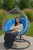 A woman sleeping in a hanging egg chair outdoors. Anteprima dell’immagine prodotto