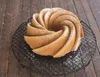 A bundt cake dusted with powdered sugar sits on a cooling rack on a wooden surface. Podgląd zdjęcia produktu