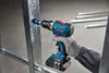 A person wearing a glove is using a Bosch drill to make a hole in a metal frame. Náhled obrázku produktu