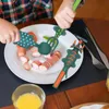 A child is using dinosaur-shaped utensils to eat sausages from a plate. Produktbild-Vorschau