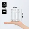 A hand holding a glass jar with dimensions and weight indicated. Anteprima dell’immagine prodotto