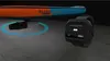 A stand-up paddleboard with an attached electric motor and a smartwatch controller. Podgląd zdjęcia produktu