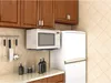 A kitchen scene with a microwave mounted above a counter, next to a refrigerator. Náhľad obrázku produktu