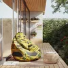 A bean bag chair with a car print sits on a wooden deck next to a small woven stool, with plants and a stone wall in the background. Náhľad obrázku produktu