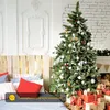 A decorated Christmas tree stands in a bedroom setting, with gifts piled at its base and pillows on a bed in the foreground. Produktbild-Vorschau