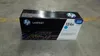 A product box for an HP toner cartridge sits on a concrete floor. Voir les images du produit