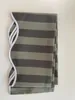 A folded striped fabric awning valance with a decorative white trim on a white background. Produktbild-Vorschau