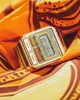 A gold Casio digital watch rests on a patterned orange and brown fabric. Podgląd zdjęcia produktu
