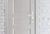A close-up view of a white door with a white door handle and lock, set against a white brick wall. Anteprima dell’immagine prodotto