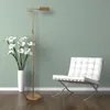 A floor lamp and a chair are placed against a wall, with a vase of flowers. Produktbild-Vorschau