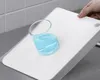 A hand is holding a white cutting board with a glass of blue liquid on it, placed on a countertop. Voir les images du produit