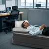 A man is lying on an inflatable mattress in an office setting. Náhľad obrázku produktu