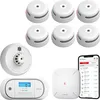 A collection of smart home safety devices including smoke detectors, a carbon monoxide detector, a heat detector, and a base station, along with a smartphone displaying a connected app. Produktbild-Vorschau