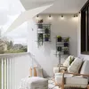 A balcony furnished with seating, an umbrella, and plants, showcasing a lifestyle setting. Produktbild-Vorschau