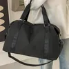 A person is holding a black duffel bag. Voir les images du produit