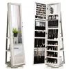 A full-length jewelry cabinet with a mirror is shown, open to reveal its interior storage compartments. The cabinet is white with a wood grain texture. The mirror is on the left side, and the right side is open, displaying various jewelry and cosmetic item Voir les images du produit