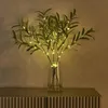 A vase of artificial olive branches with LED lights sits on a textured surface. Produktbild-Vorschau