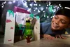 A young boy is playing with a Minecraft toy under a blanket fort decorated with fairy lights. Náhled obrázku produktu
