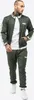A man wearing a green tracksuit with white stripes on the sleeves and pants. Náhled obrázku produktu