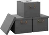 Three grey fabric storage boxes with brown handles are arranged on a white background. One box is stacked on top of two others, and its lid is propped open, revealing a white shirt inside. The lid of one of the bottom boxes is also open and leaning against Produktbild-Vorschau
