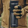 A person wearing gloves and a jacket holds a Contigo travel mug outdoors. Anteprima dell’immagine prodotto